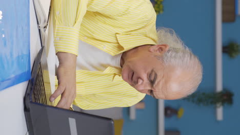 Vertical-video-of-Home-office-worker-old-man-working-on-laptop-stressed.