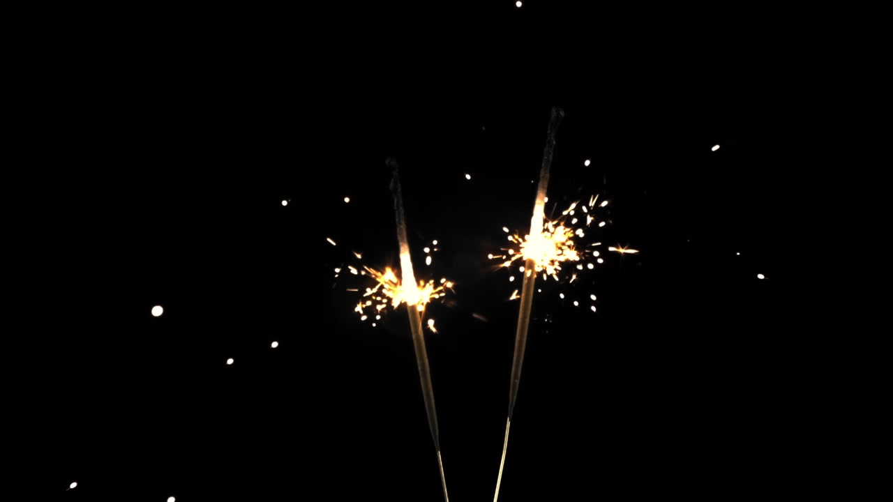 Scintille dorate che volano da stelle filanti accese su sfondo nero