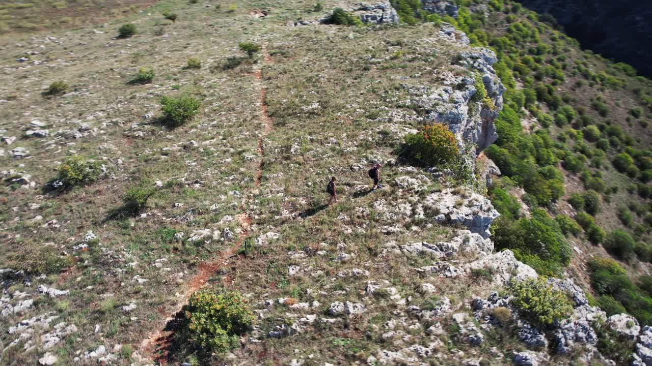 drone volando en gran movimiento circular alrededor de 2 personas caminando al borde de un gran cráter en 4k
