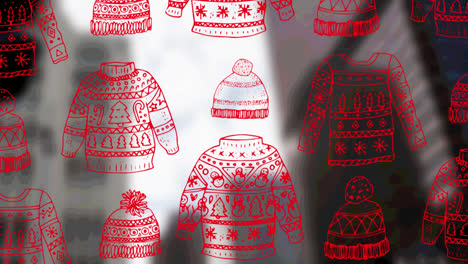 Animation-of-christmas-sweatshirts-and-hats-over-cityscape-background