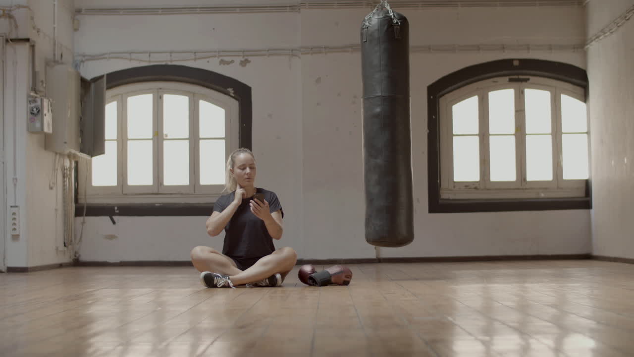 Long shot of woman taking her pulse before boxing workout