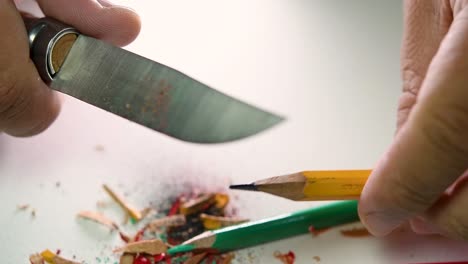 Footage-of-hands-slowly-sharpening-a-pencil-and-some-coloured-pencils-with-a-sharp-knife