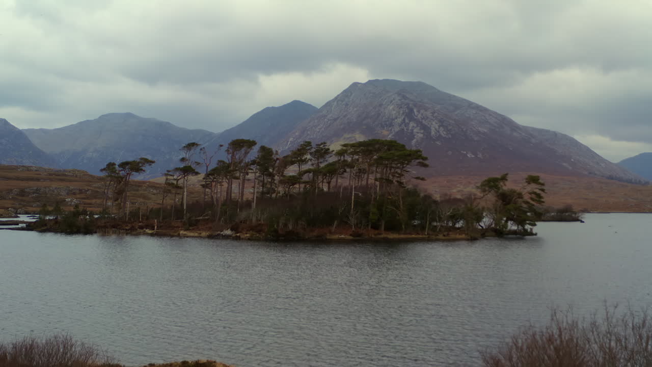Aerial dolly of Pine Island under cloudy sky with the Twelve Bens in the background. Connemara