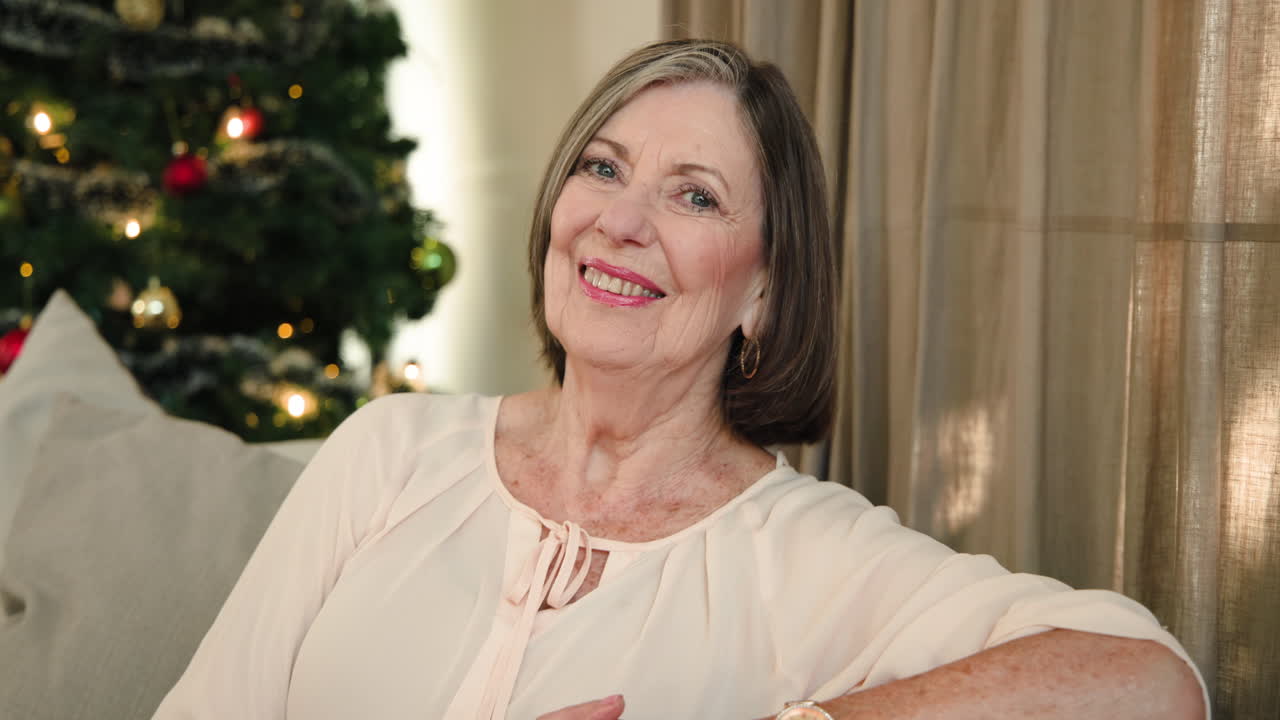 Smiling senior woman relaxing at home with Christmas tree in background