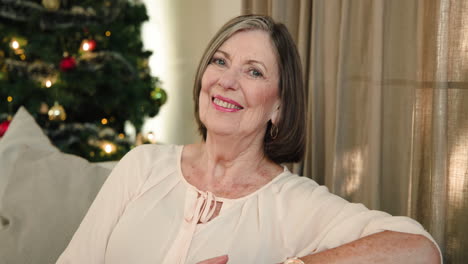 smiling senior woman relaxing at home with christmas tree in background