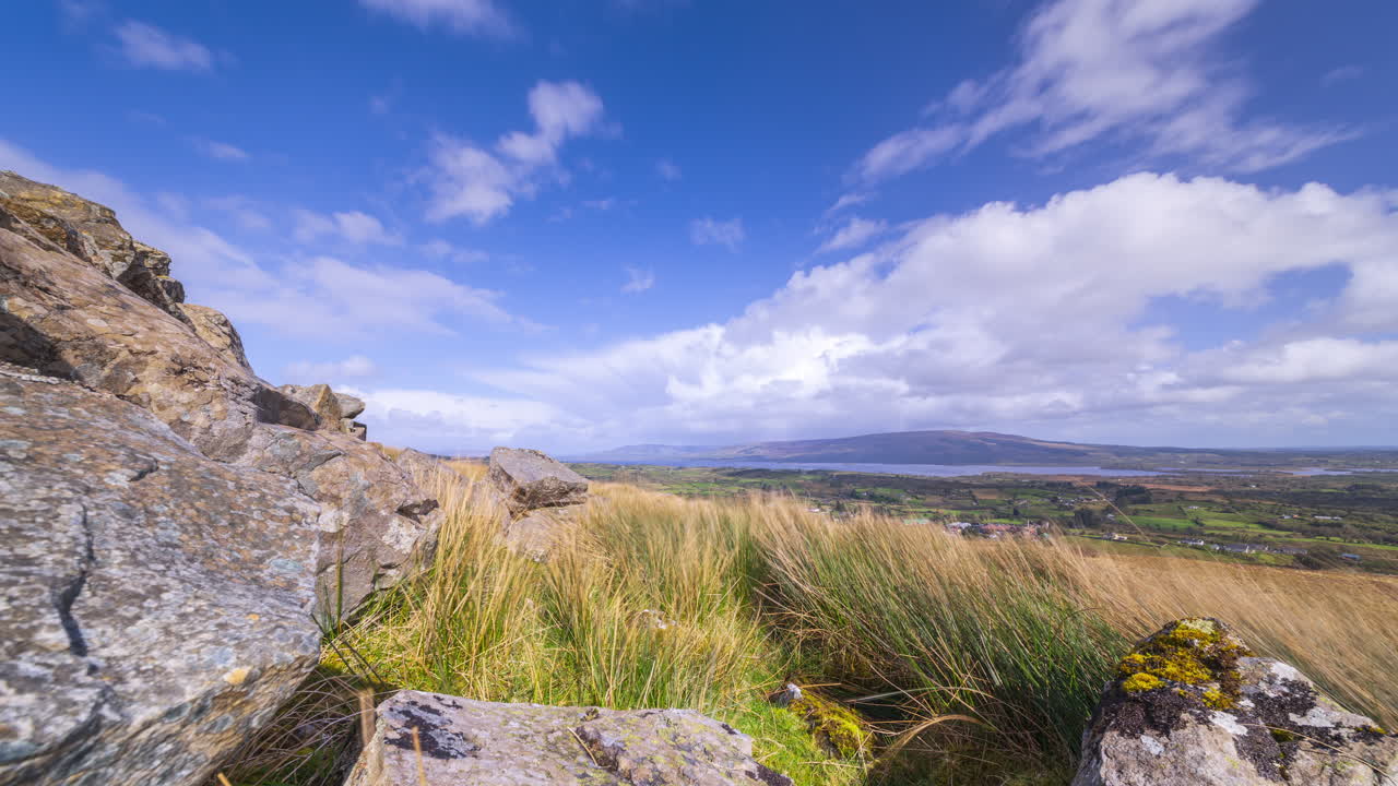 Time lapse of rural landscape with rocky foreground and hills and lake in the distance with passing storm showers during a spring day in Arigna mountains in county Leitrim in Ireland