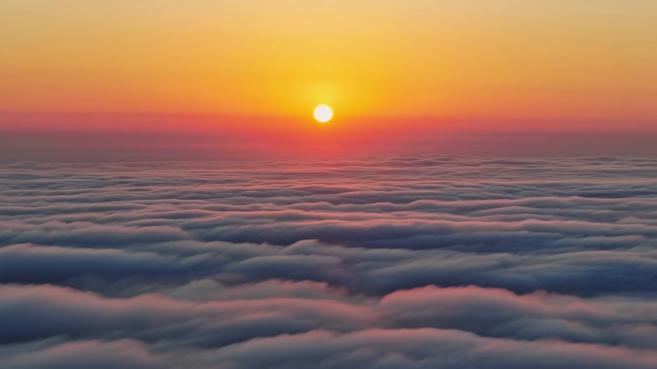 Une vue aérienne sereine d'un magnifique coucher de soleil au-dessus des nuages, capturée depuis la perspective de l'horizon océanique. Les teintes chaudes d'orange et de jaune créent une atmosphère paisible et relaxante, parfaite.