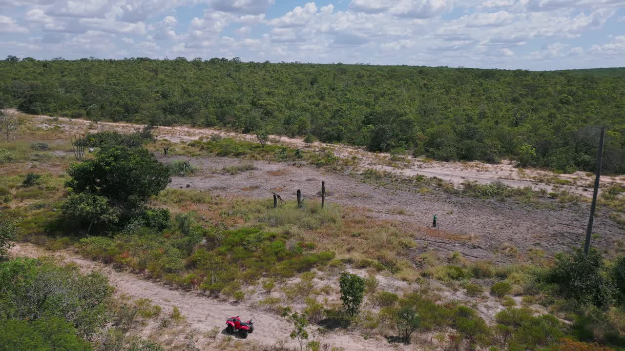 Paesaggio del Cerrado brasiliano con letto del fiume secco e screpolato, vegetazione degradata e ricercatori accanto a un quad rosso che studiano la siccità, l'erosione del suolo e gli impatti climatici