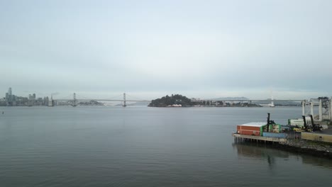 the san francisco bay bridge appears in this distance, connecting san francisco and oakland in this aerial drone view.