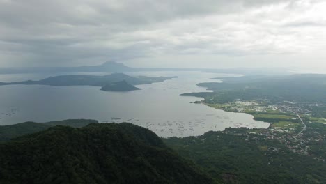 Ojo-Escénico-Que-Captura-La-Vista-Del-Volcán-Taal-Rodeado-Por-El-Tranquilo-Lago-Taal-Brumoso-Bajo-Un-Cielo-Nublado