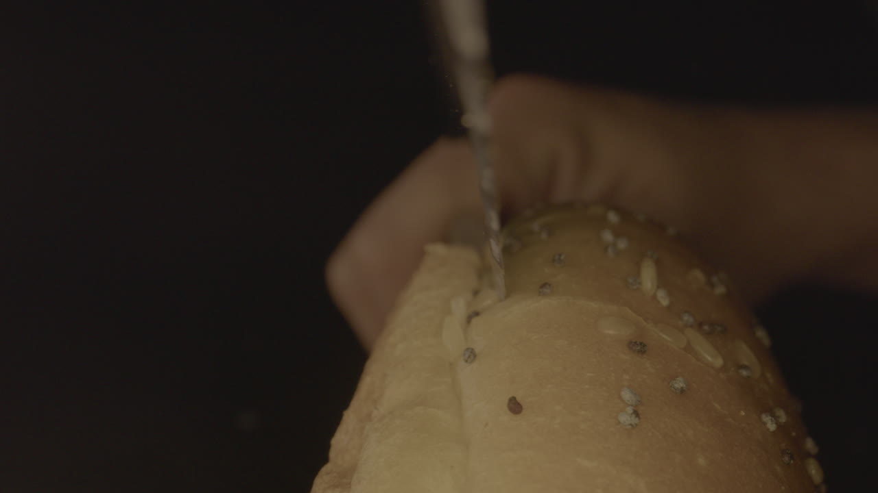 Macro shot of hamburger bun being cut open with bread knife