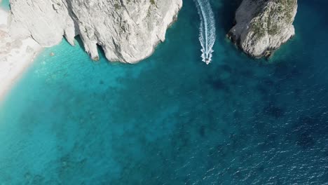 drone hovers above small islands on the island of zakynthos, greece, following a small boat that emerges between two islands