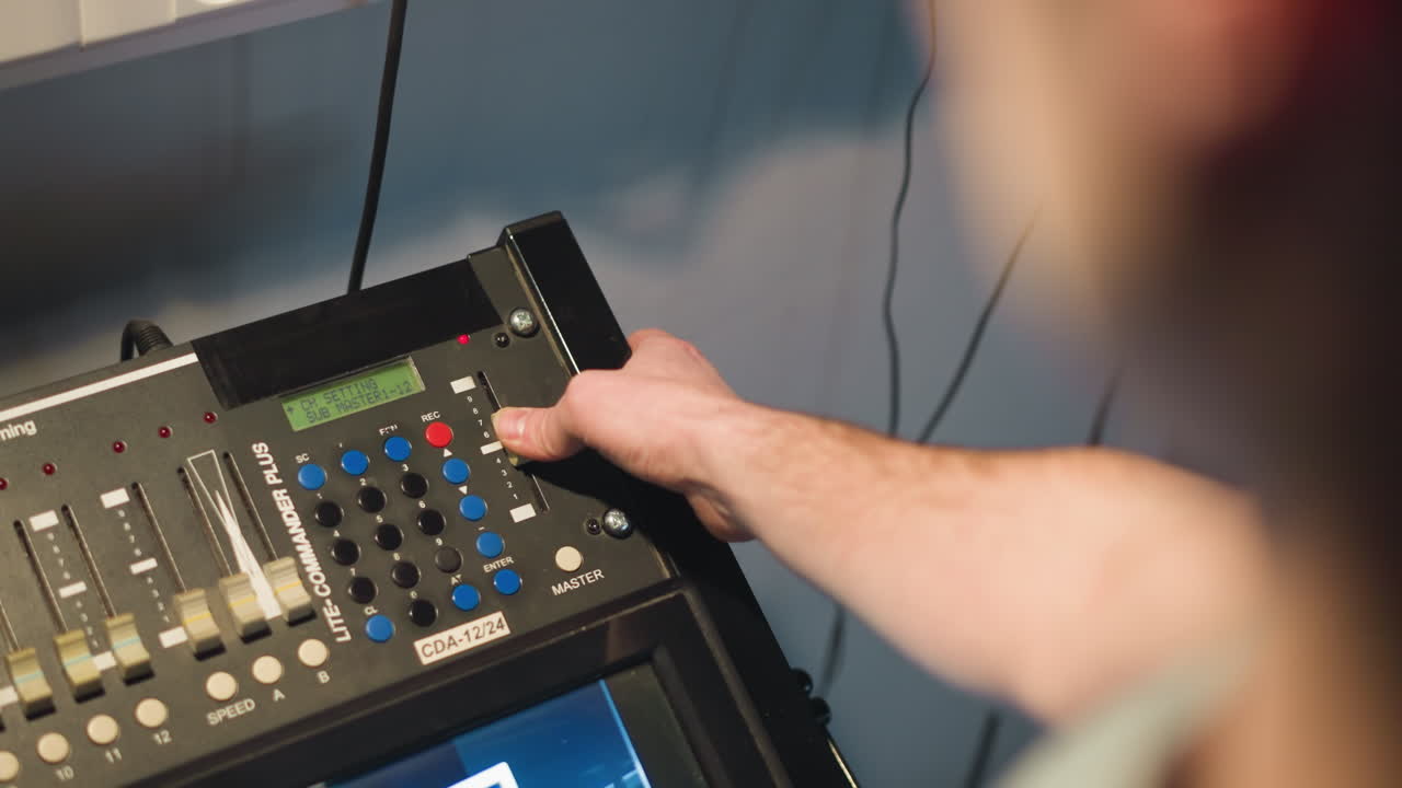 Close-up of hand adjusting control panel on professional multimedia equipment in studio. User presses buttons and adjusts settings on video mixing console, cinematic lighting and technology in use