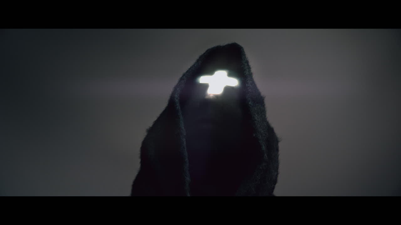 Masked man with cross of light glowing on his face moves his head up