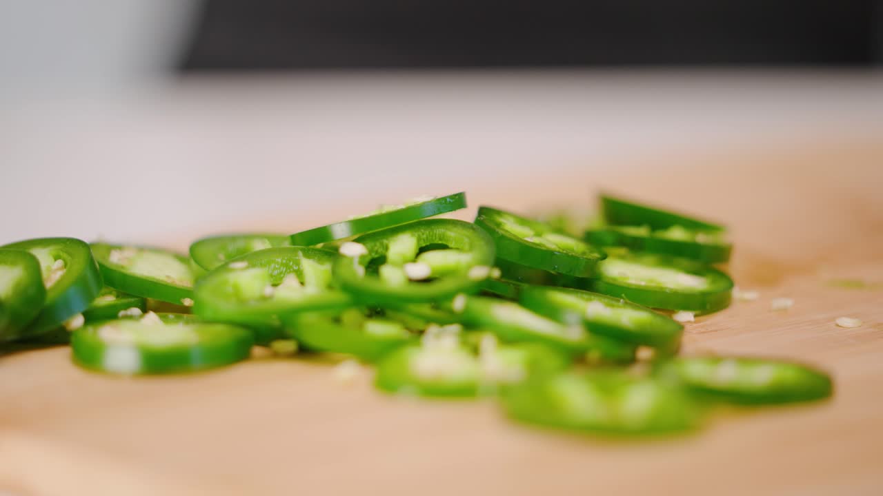 슬로우 모션으로 얇게 썬 할라피뇨 고추를 자른 고추 더미에 떨어뜨리는 백인 손