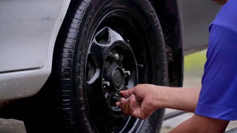 close up shot of man hand fit the nut on the rim after replace the car wheel