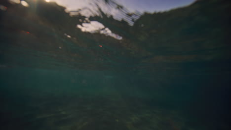 underwater view of breaking wave with mystical light on surface