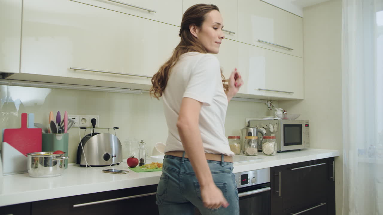 Donna felice che balla in cucina moderna. Donna gioiosa che si diverte.
