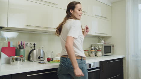 happy woman dancing at modern kitchen. joyful woman having fun.