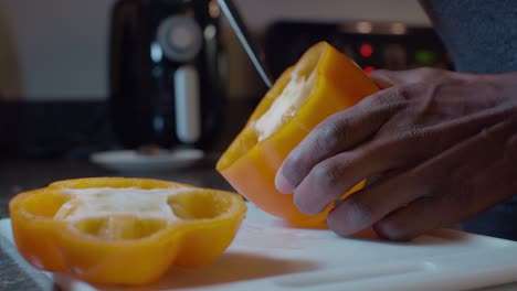 a black cook removing pepper carpelloid and seed from fresh yellow bell pepper pod