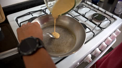 Slow-motion-of-a-mexican-latin-man-pouring-batter-on-a-stainless-steel-pan-making-a-heart-shape-pancake-for-his-wife-on-Valentines