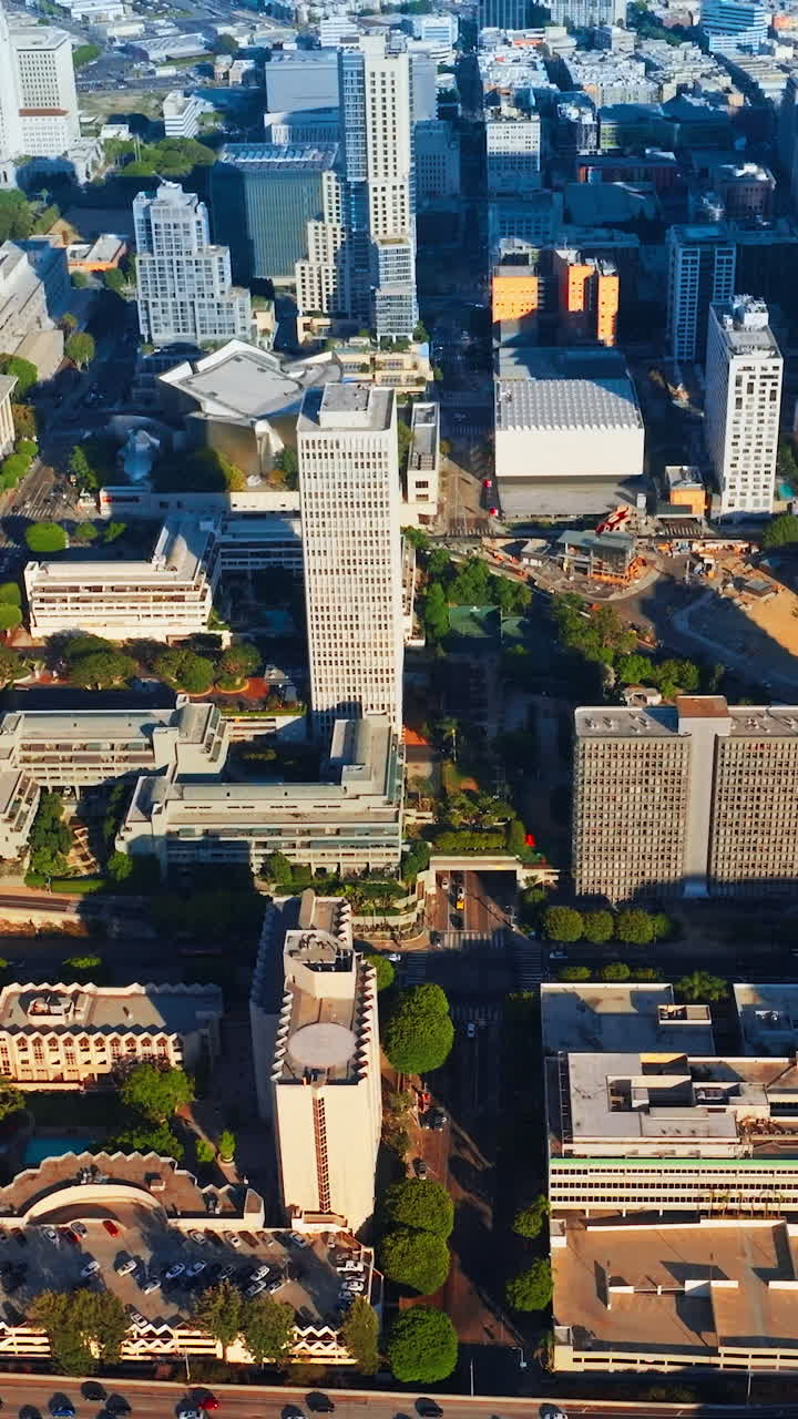 Rising above sunlit Los Angeles downtown. Crazy traffic on the roads of metropolis from aerial view. Vertical video