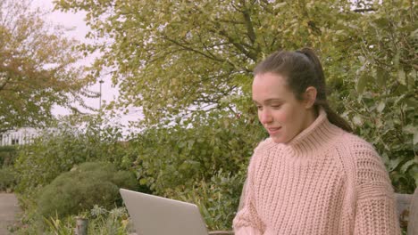 Female-working-on-a-laptop-in-a-park-smiling