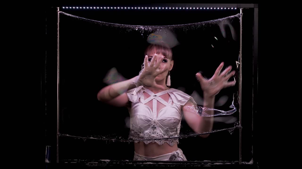 девушка делает фокусы с мыльными пузырями она держит руки на мыльной стене играет выдувает пузырь