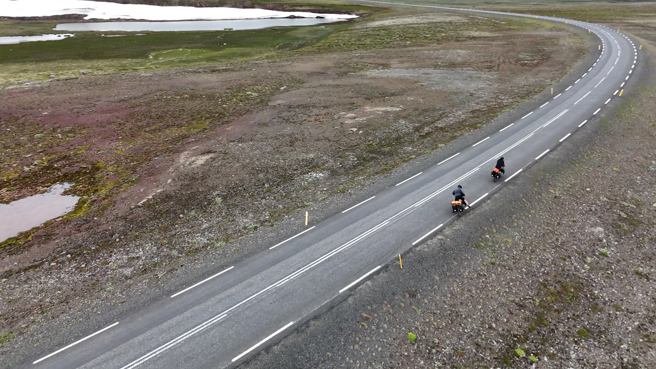 東アイスランドの海岸沿いの道を走る2人のサイクリストをドローンで空撮。フィヨルド、山々、そして曇り空の下に広がる風景は、冒険旅行、孤独、そしてFreepikを象徴しています。