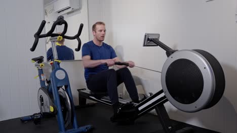 hombre caucásico de mediana edad participando en un entrenamiento de remo en el gimnasio en casa