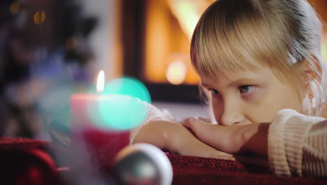 portrait of a child looks at a candle makes a wish on christmas eve