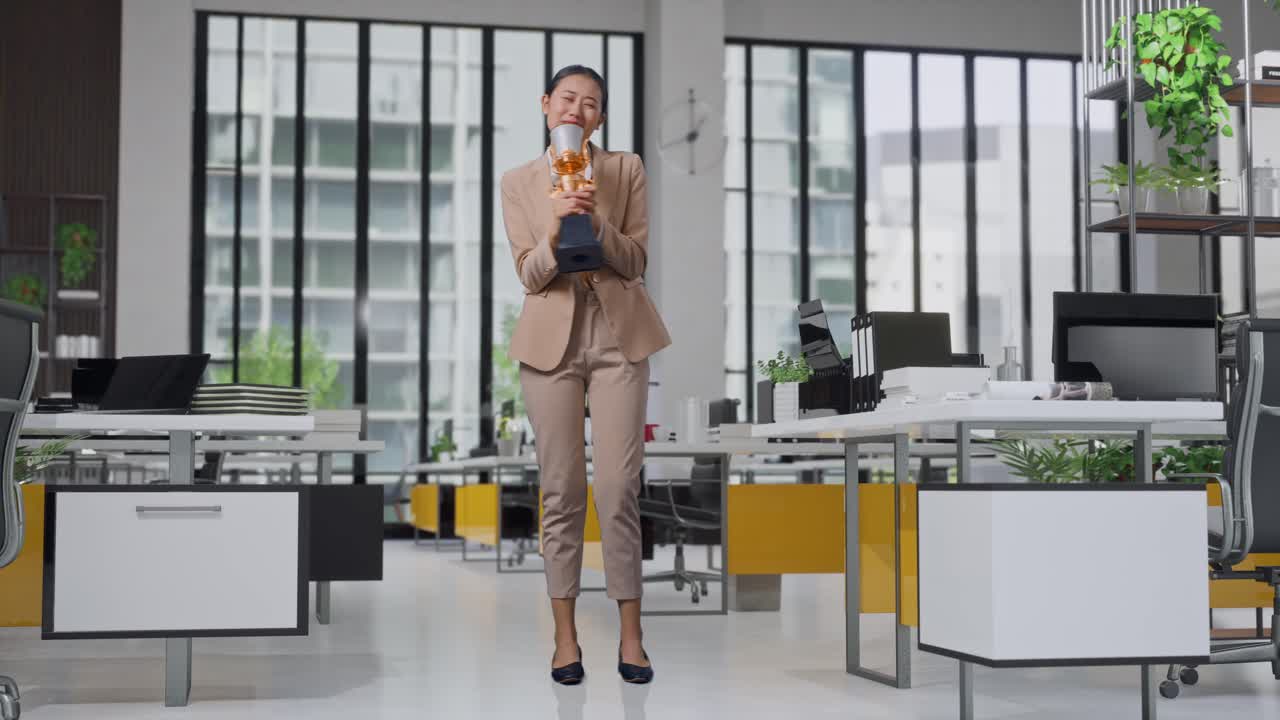 Full Body Of Asian Business Woman In A Suit With A Gold Medal Singing On A Gold Trophy Celebrating Winning As The First Winner In The Office