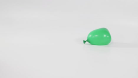 a green balloon drops and bounces on the ground