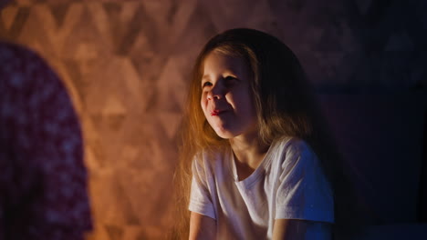 Una-Niña-Bonita-Mastica-Comida-Mirando-A-Sus-Padres-En-Una-Habitación-Oscura