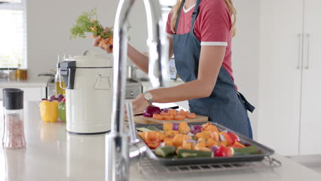 Happy-caucasian-woman-wearing-apron-and-throwing-waste-out-in-kitchen,-slow-motion