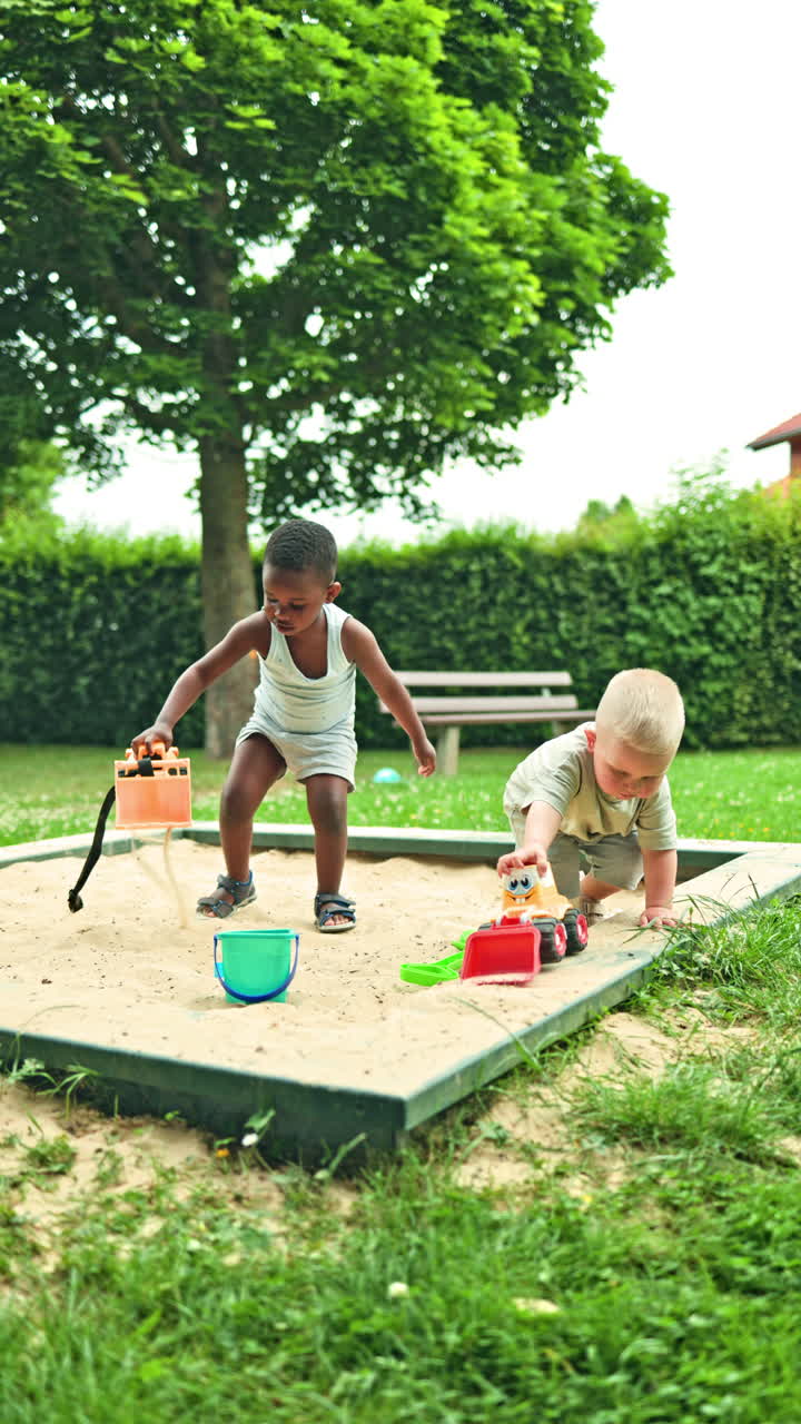 An African boy and a European boy play together on a playground. Communication of children of different nationalities in a sandbox. Integration of children among themselves