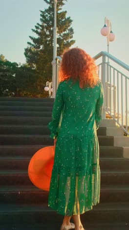 woman walking down stairs in green dress