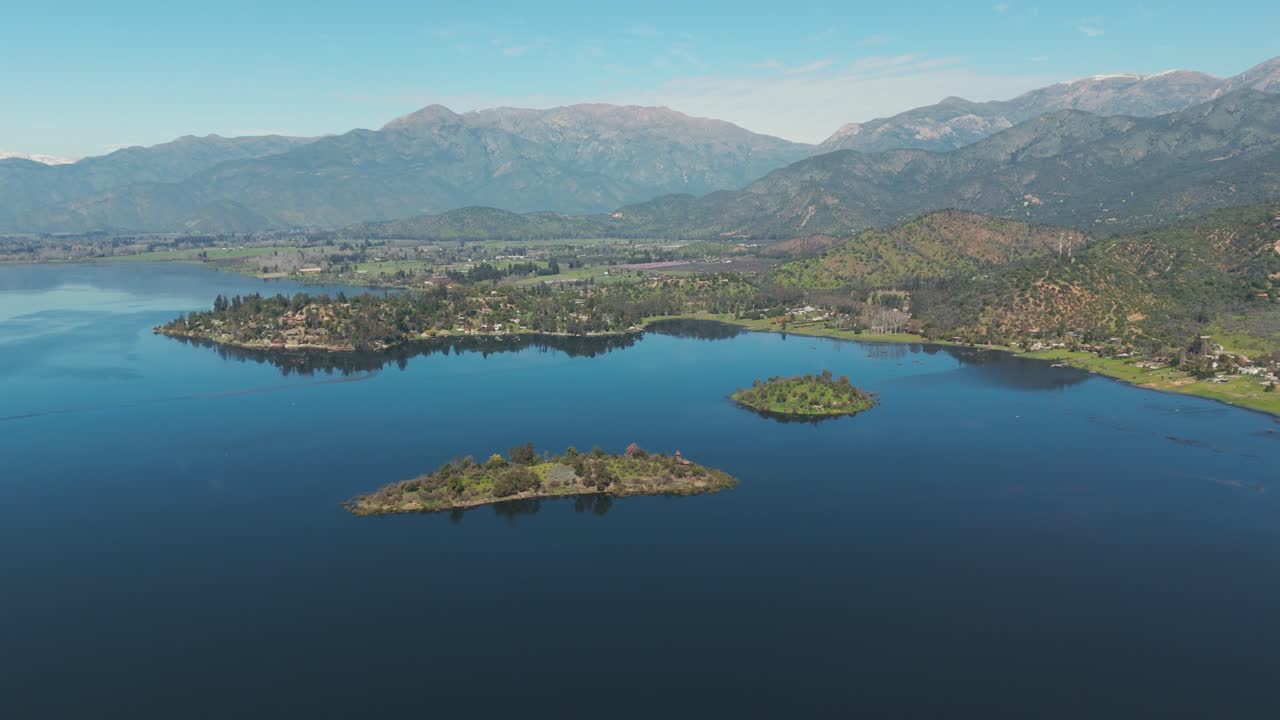 vista aérea de la laguna de aculeo en valparaíso, chile, que muestra islas exuberantes y montañas lejanas bajo un cielo azul claro