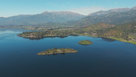 aerial view of aculeo lagoon in valparaíso, chile, showcasing lush islands and distant mountains under clear blue skies