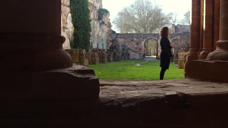 young redhead girl admiring the ruins of a monastery in spain