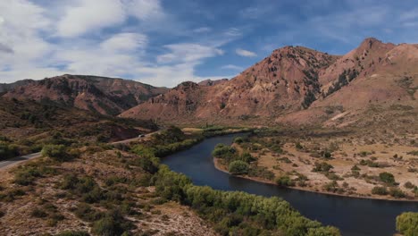 Drone-view-of-a-river-with-mountains-and-a-road-with-a-truck-passing-by