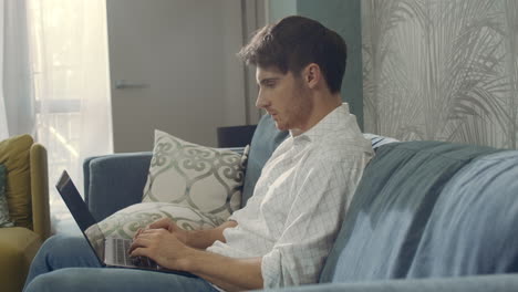 Focused-man-looking-laptop-screen-indoors.-Thoughtful-guy-working-computer-hotel