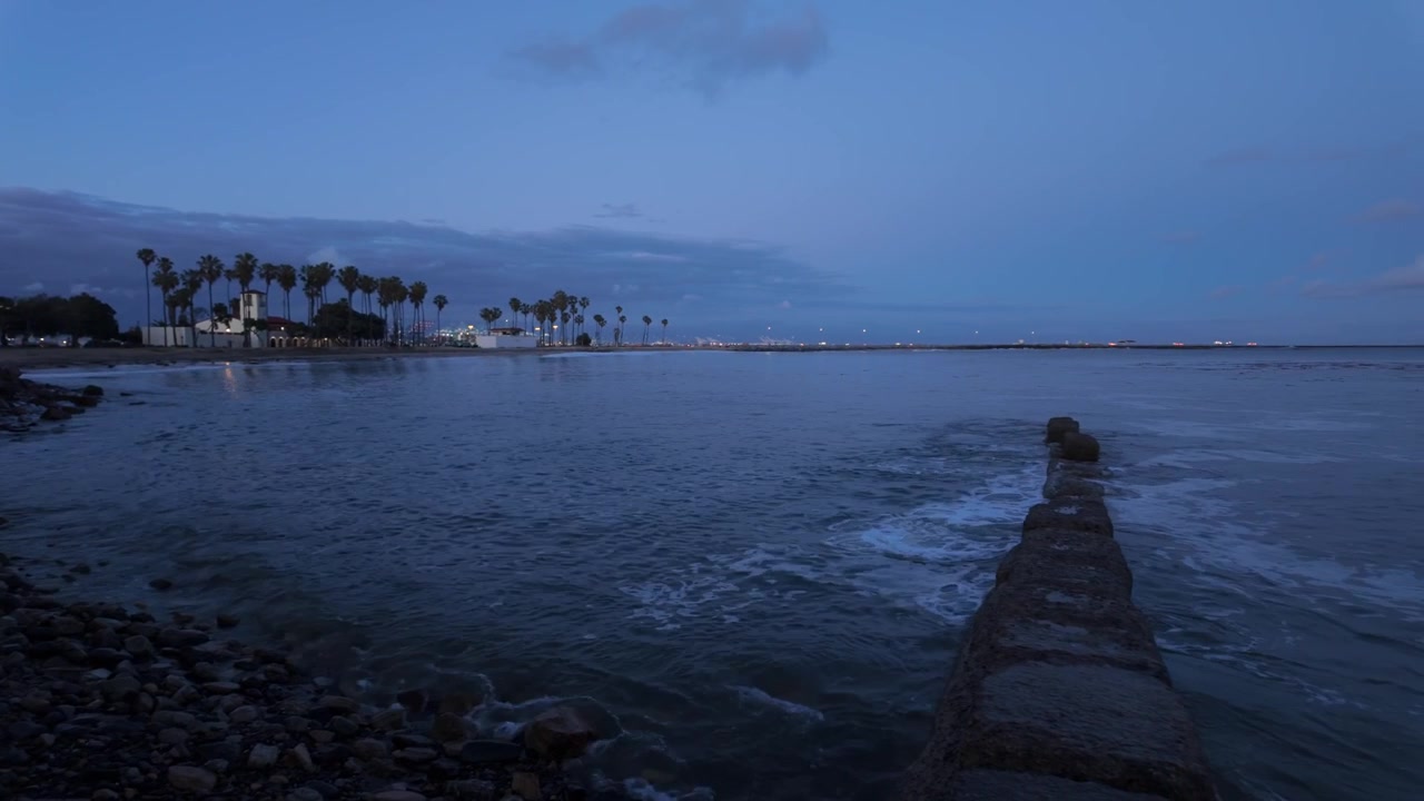 Panorâmica ampla com gimbal da Praia de Cabrillo com o Porto de Los Angeles ao anoitecer no Sul da Califórnia. 4K.