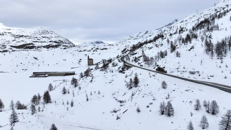 Black-asphalt-road-climbing-up-over-the-with-snow-covered-Simplon-pass-on-a-cloudy-day