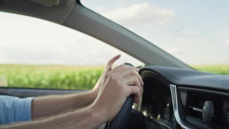 Close-up-of-caucasian-man-holding-hands-on-steering-wheel-and-moving-them.