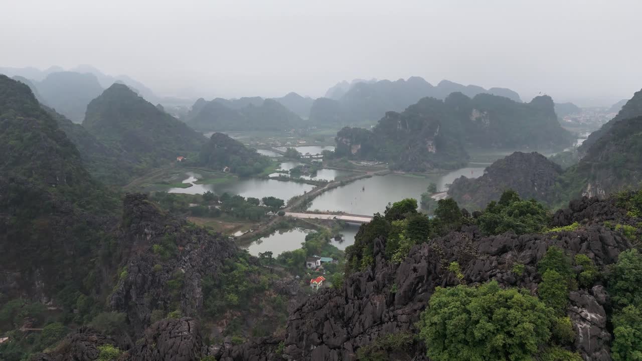 Limestone karsts, winding waterways, and lush greenery of Trang An in Ninh Binh, Vietnam viewed from above, highlighting rivers and scattered houses amid the dramatic mountain landscape