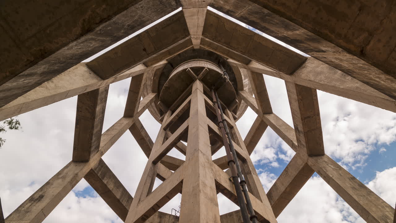 Time-lapse from inside a concrete water tower, looking up, slow cinematic camera movement, and slow-moving clouds