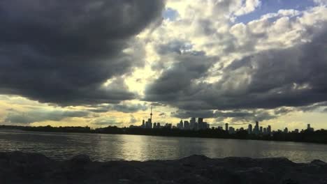 wide shot of lake and dynamic sky set against toronto city skyline in the distance