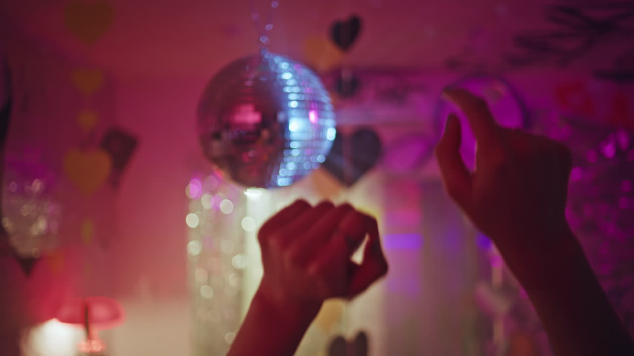 Closeup woman hands dancing under disco ball in vibrant nightclub. Girl clubber