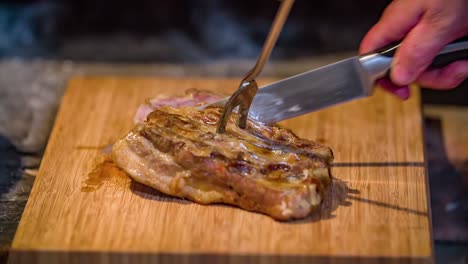 primer plano de una persona cortando un jugoso trozo de carne de cerdo en una tabla de madera